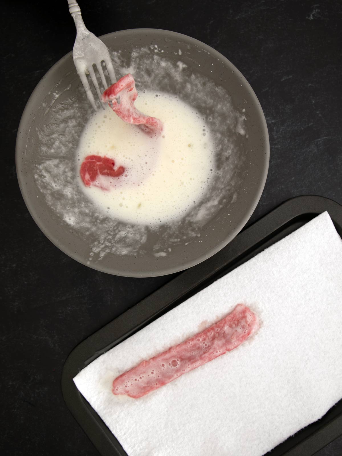 A fork is placed on a plate next to a piece of meat.