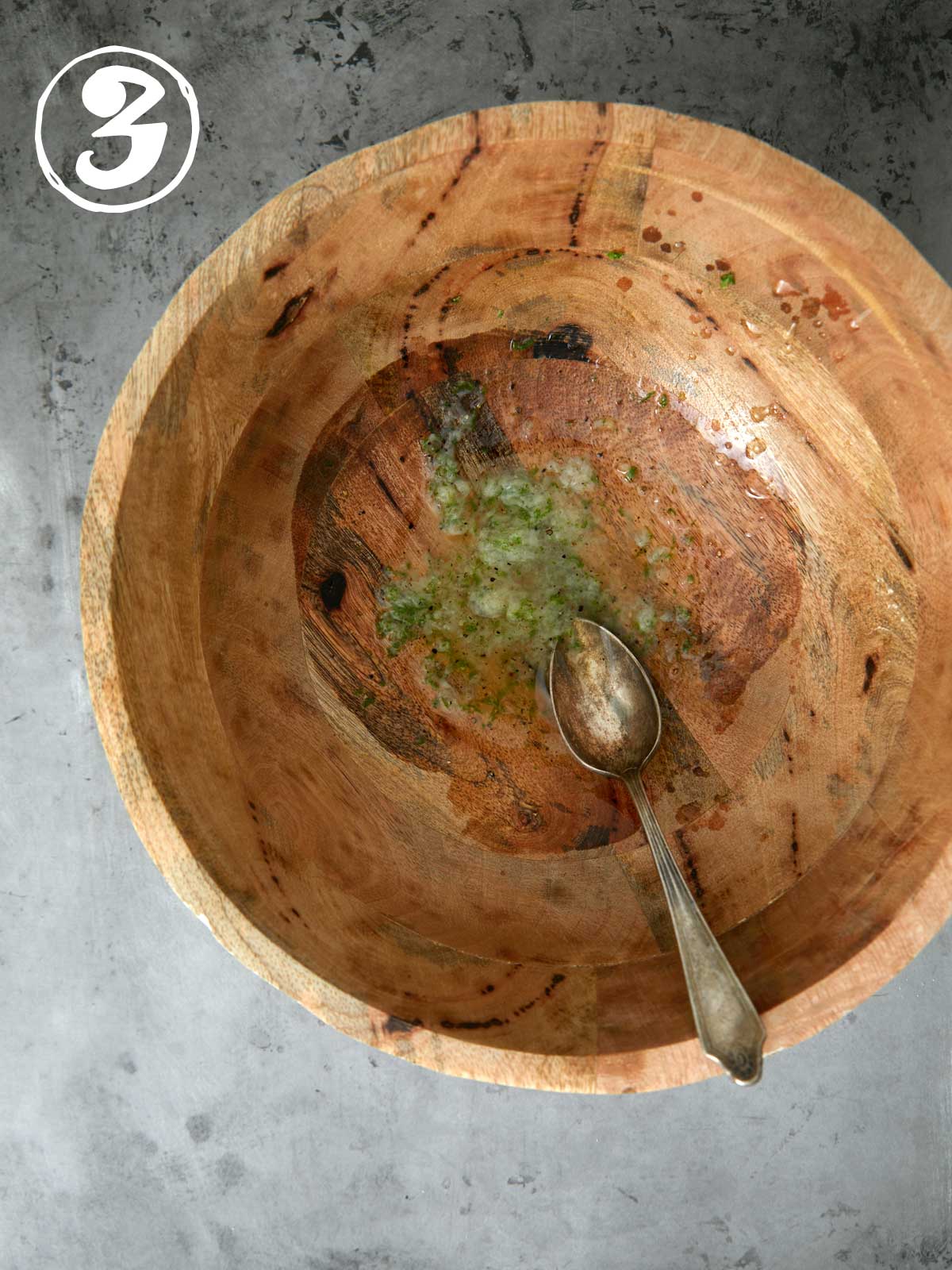 A wooden bowl with a spoon and dressing in it.