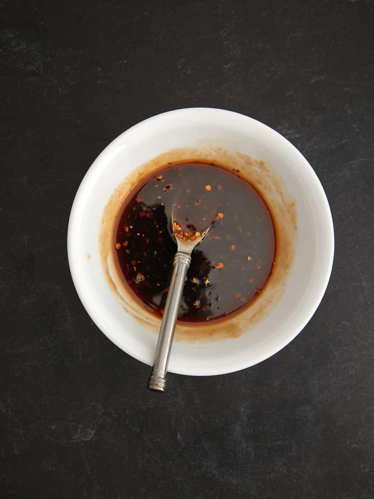 A bowl of sauce with a spoon in it.