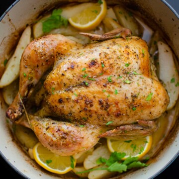 A chicken in a pan with potatoes and lemons.
