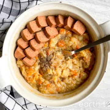 A bowl of soup with sausages and carrots.