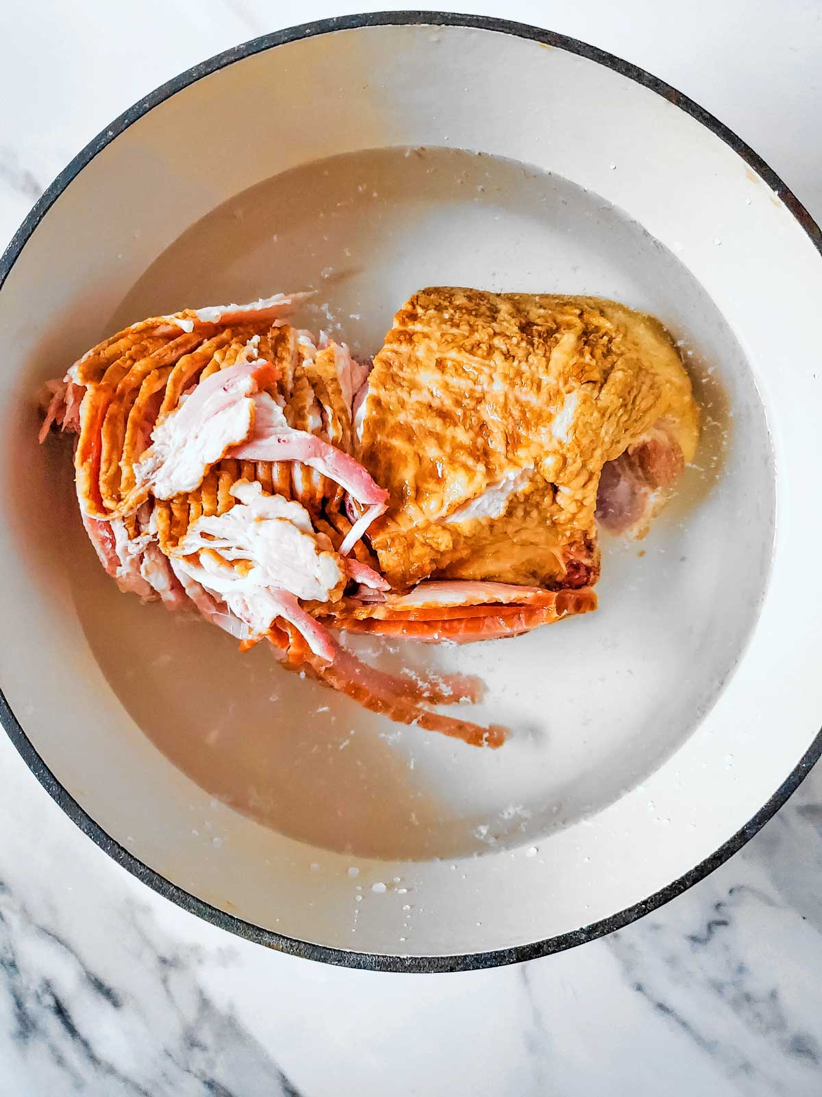 Ham bone and meat on a marble countertop.