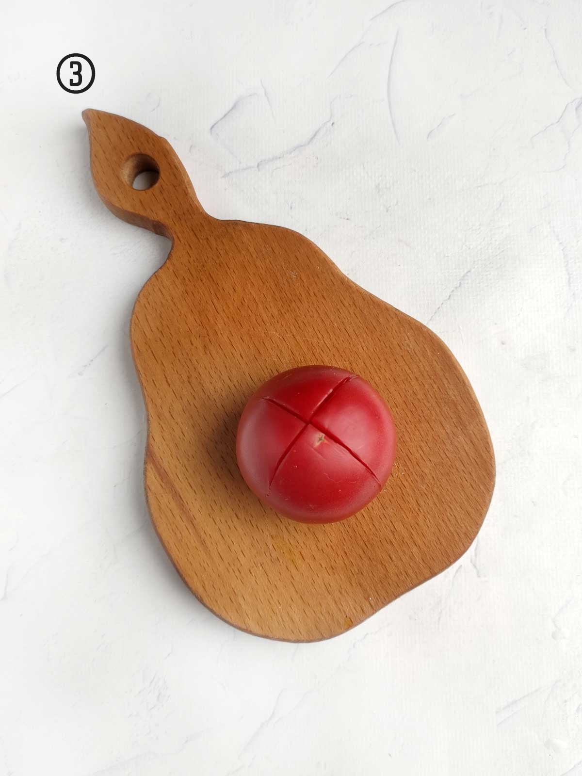 A wooden cutting board with a red tomato on it.