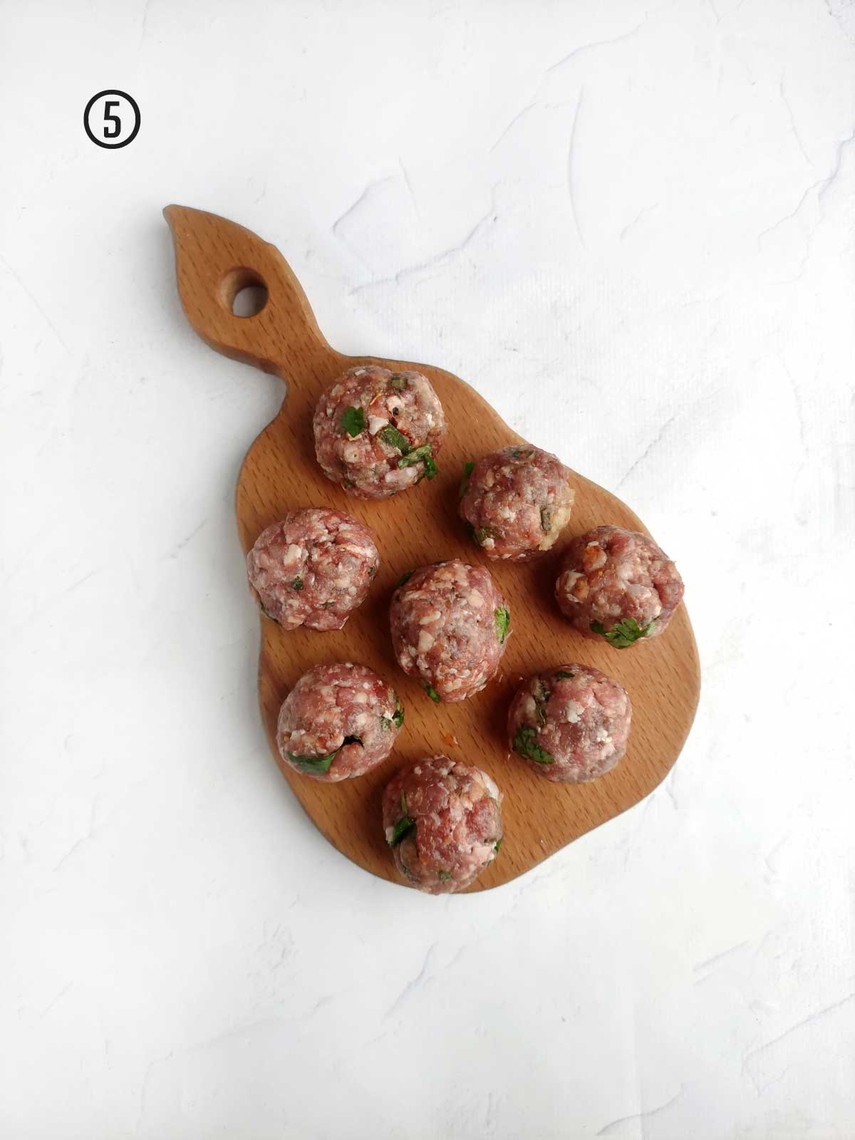 Meatballs on a wooden cutting board.
