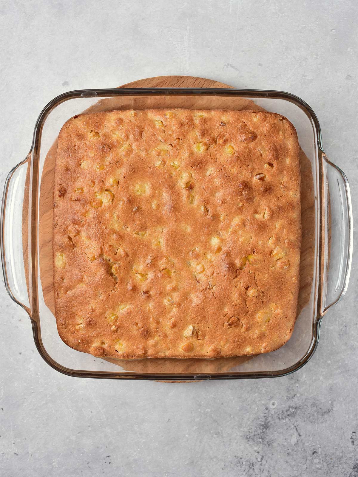 Corn casserole in a glass baking dish on a table.