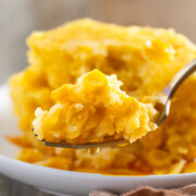 A forkful of easy corn casserole lifted from a white plate.