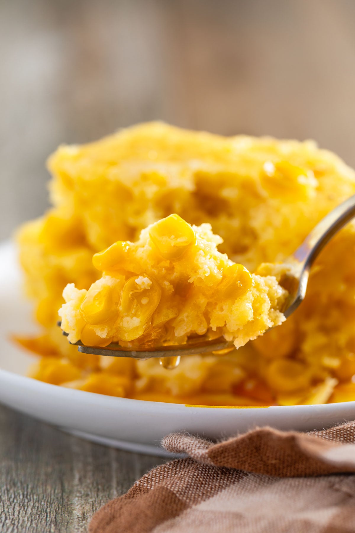 A forkful of easy corn casserole lifted from a white plate.