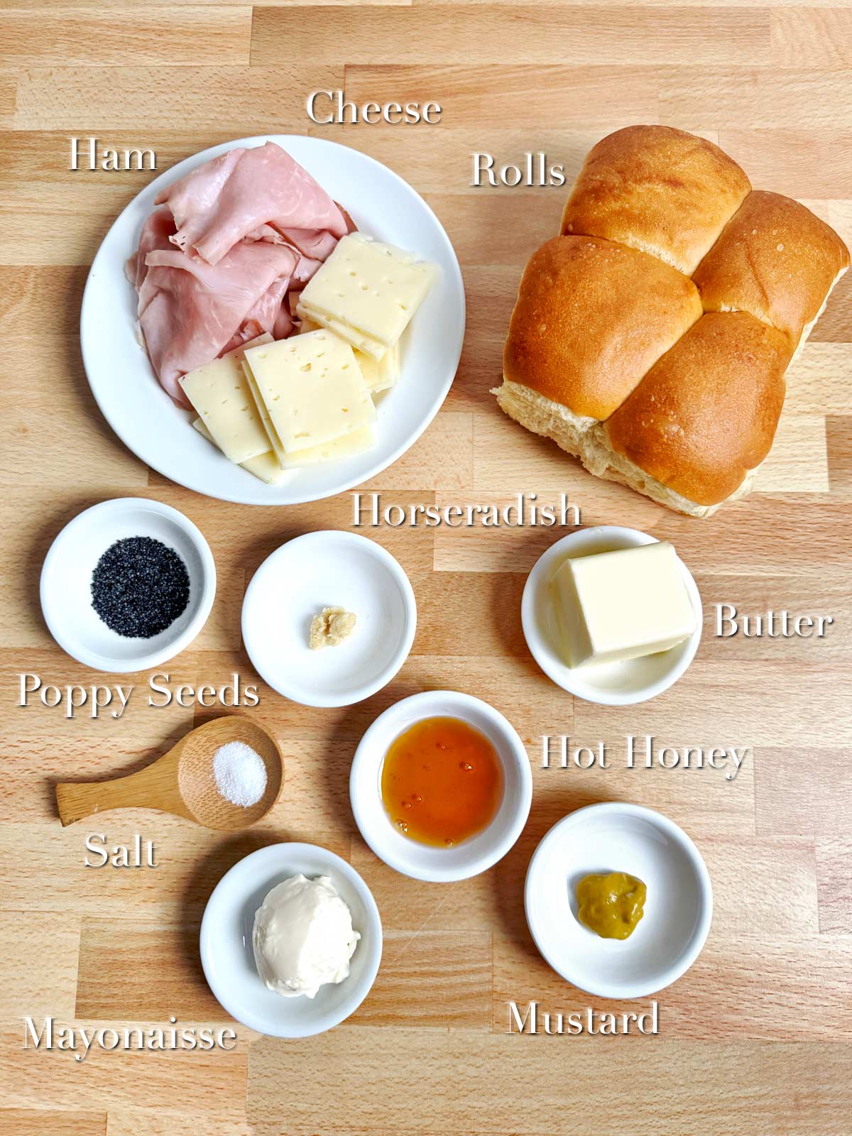 Ingredients for a ham and cheese sandwich on a wooden table.