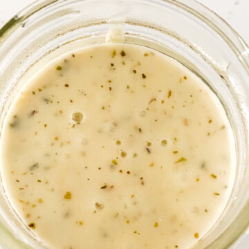 A jar of dressing in a white bowl.