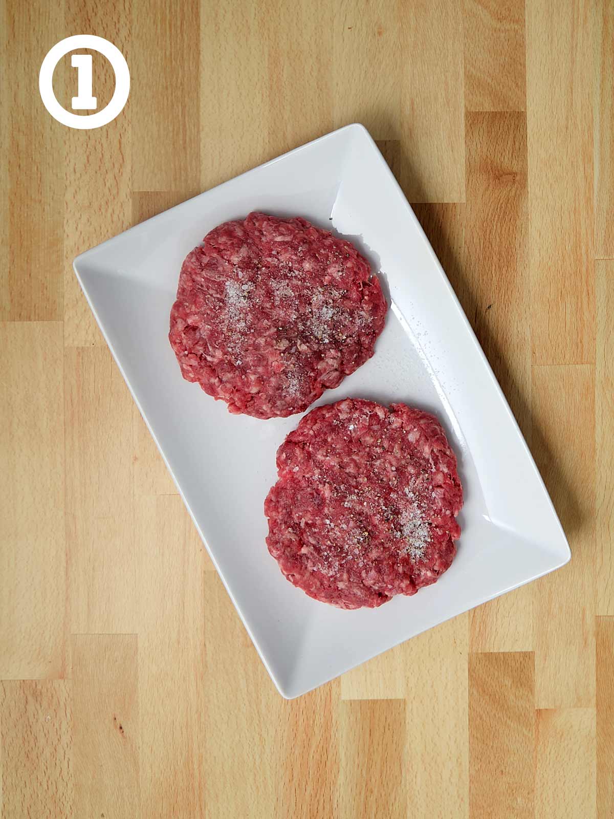 Two beef burgers on a white plate.