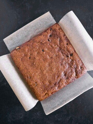An Irish Spice Cake removed from pan by overhang of parchment paper.