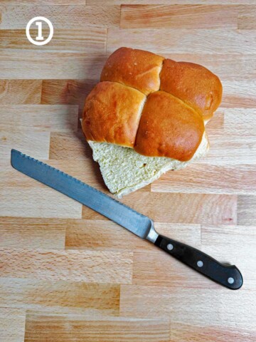 Four dinner rolls next to a knife.