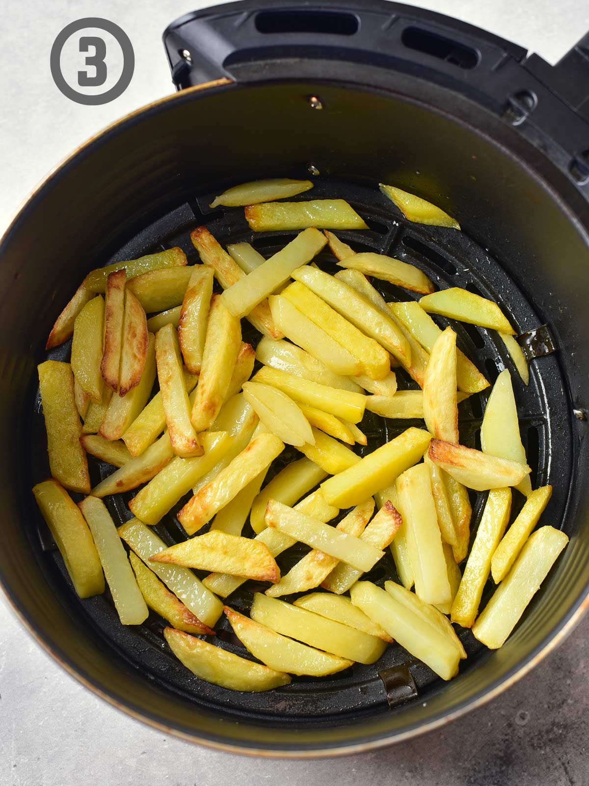 An air fryer basket with fries in it.