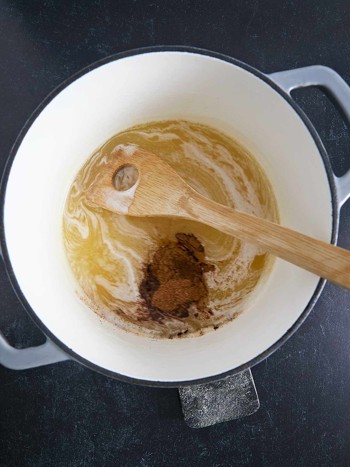 A Irish Spice Cake ingredients cooking in a pot with a wooden spoon.