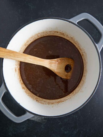 A pot of wet ingredients, accompanied by a wooden spoon.