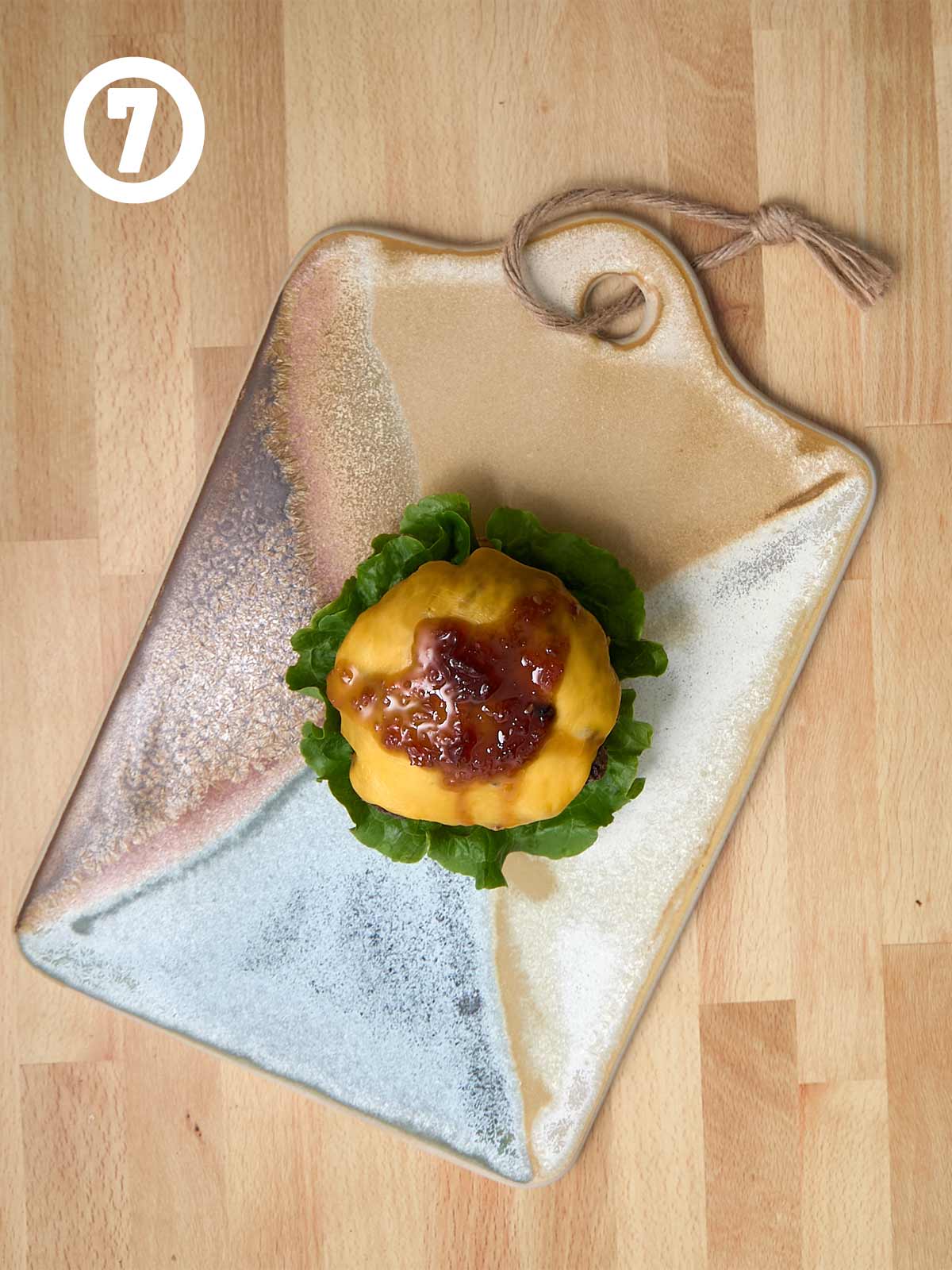 A plate with a cheesburger with sauce on it.