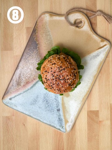 A burger with sesame seeds sits on a plate.