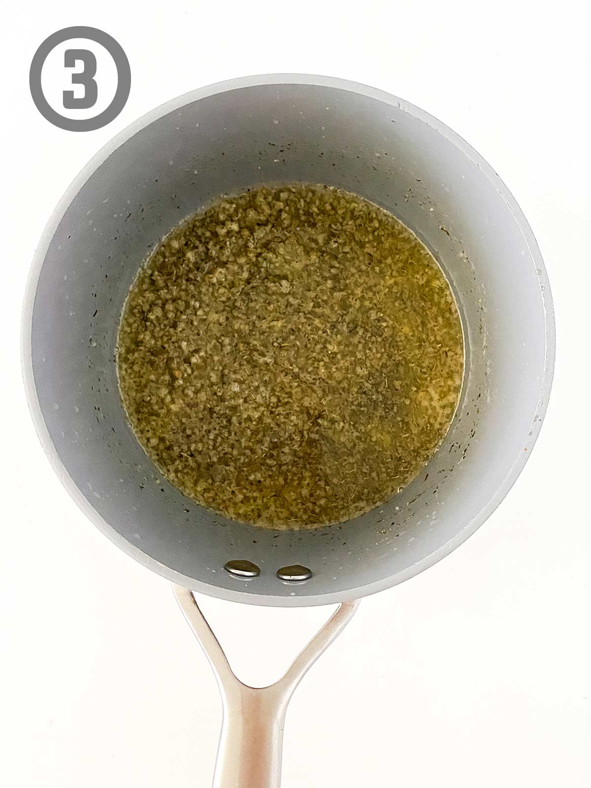 A saucepan filled with a mixture of butter and garlic and spices.