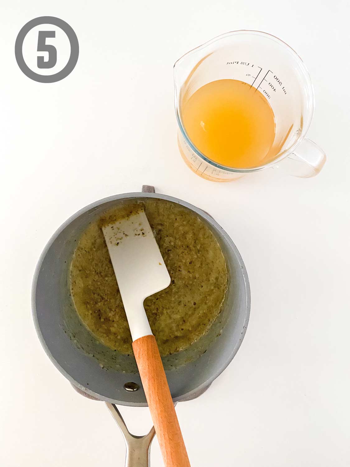 A suacepan with sauce and a wooden spoon.