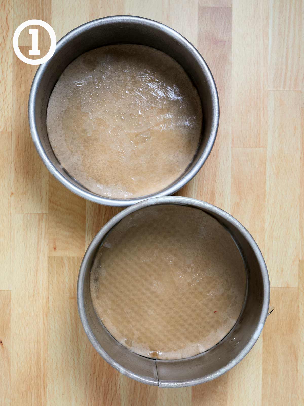 Two pans with parchment paper for Guinness chocolate cake on a wooden table.
