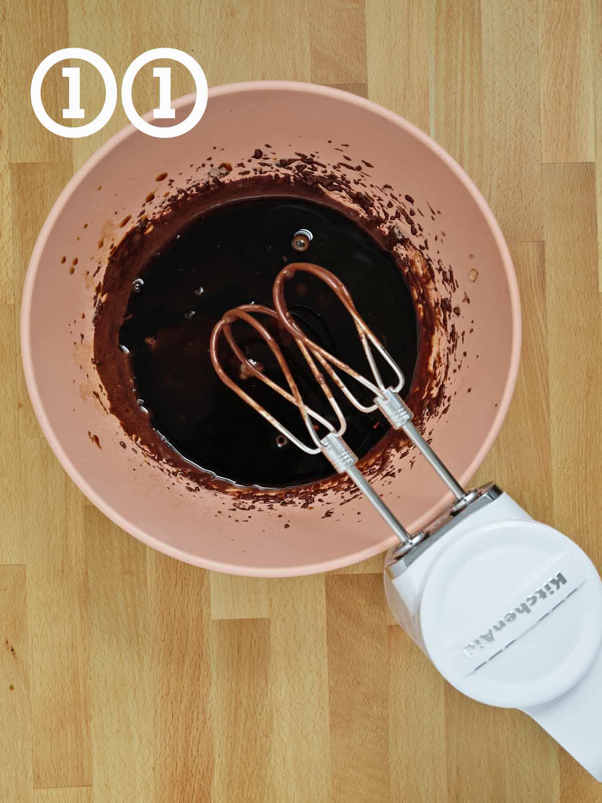 A bowl of chocolate cake batter with a mixer.