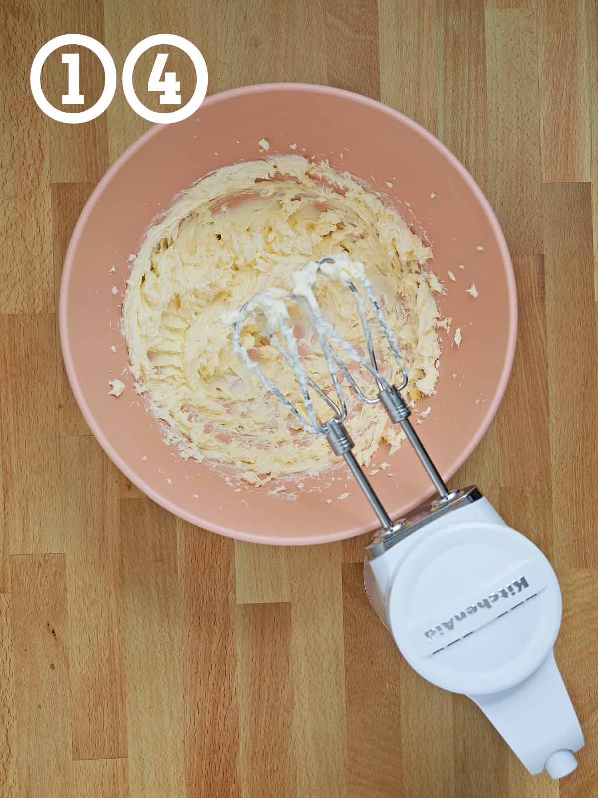 A mixer with a bowl of of frosting ingredients.