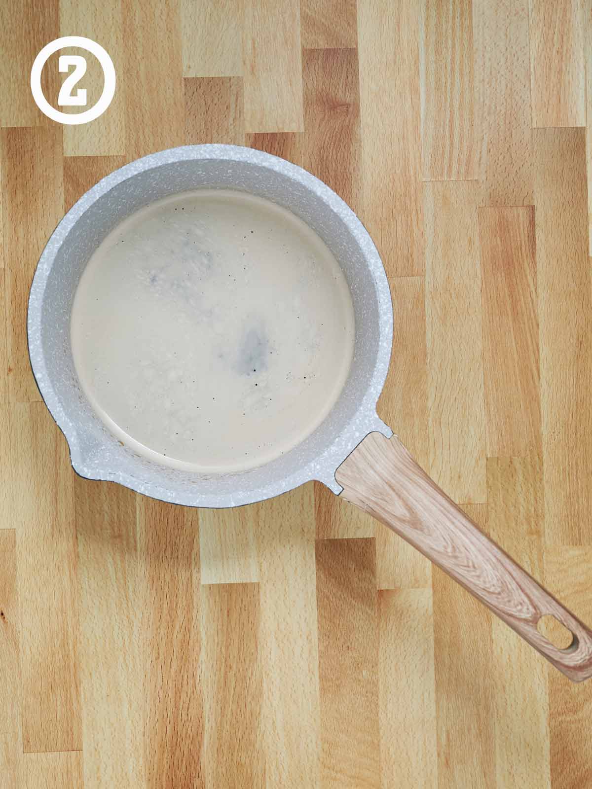 A sauce pan on a wooden table with Guinness beer.