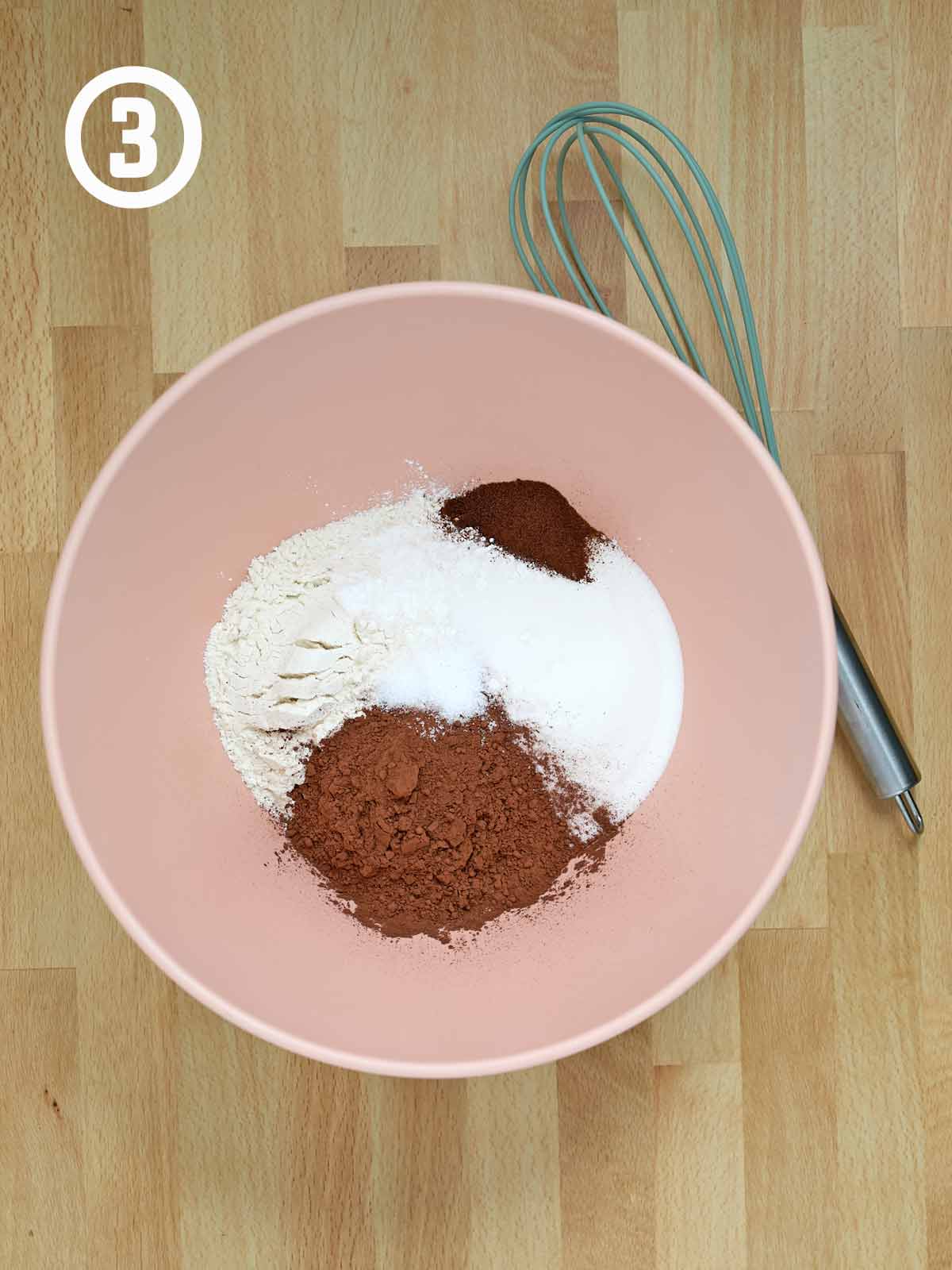A pink bowl with dry ingredients for a Guinness chocolate cake.