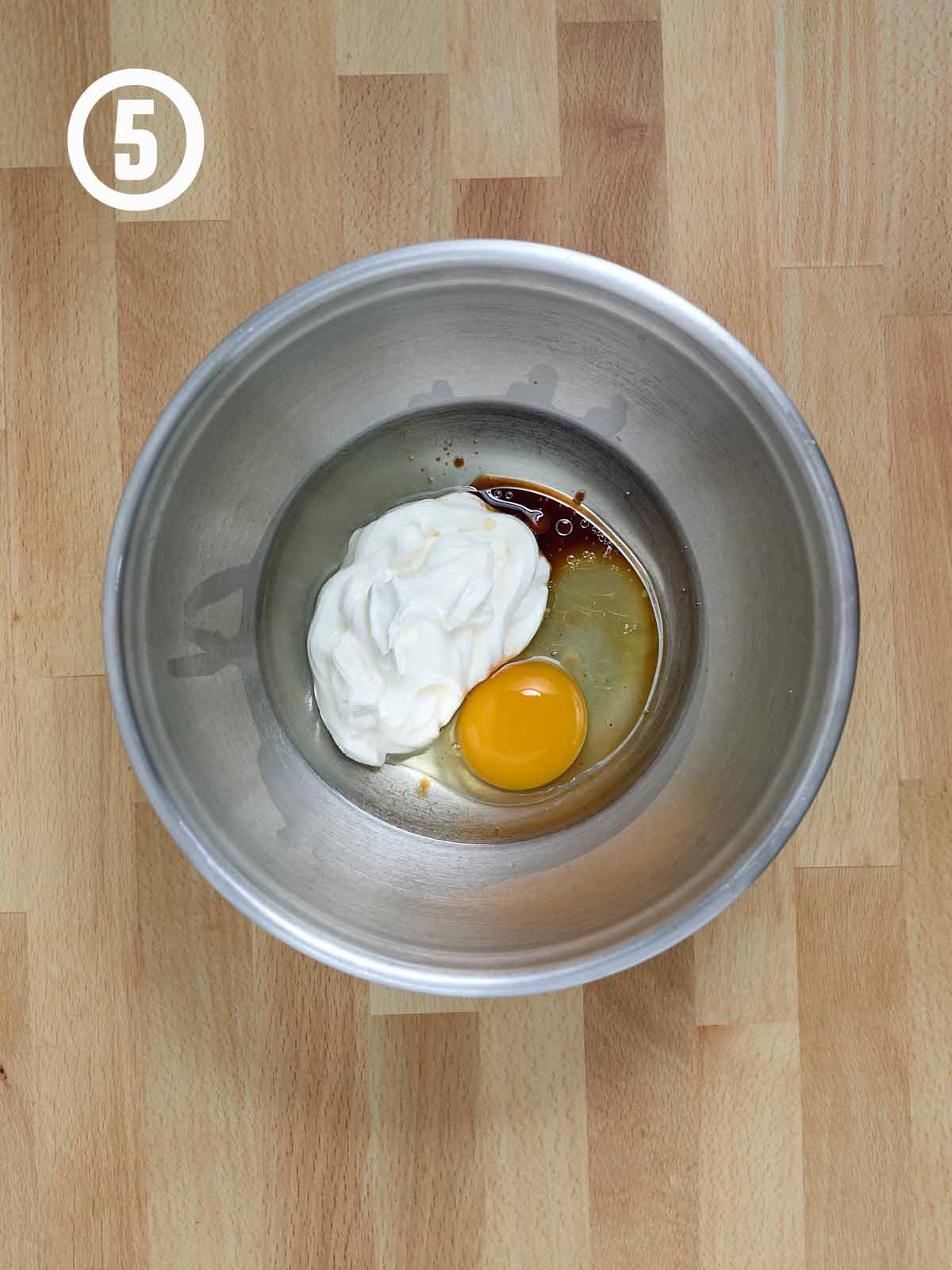 A metal bowl with an egg and sour cream in it, for making a Guinness chocolate cake.