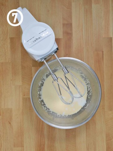 A mixer with a bowl of batter for Guinness chocolate cake on a wooden table.