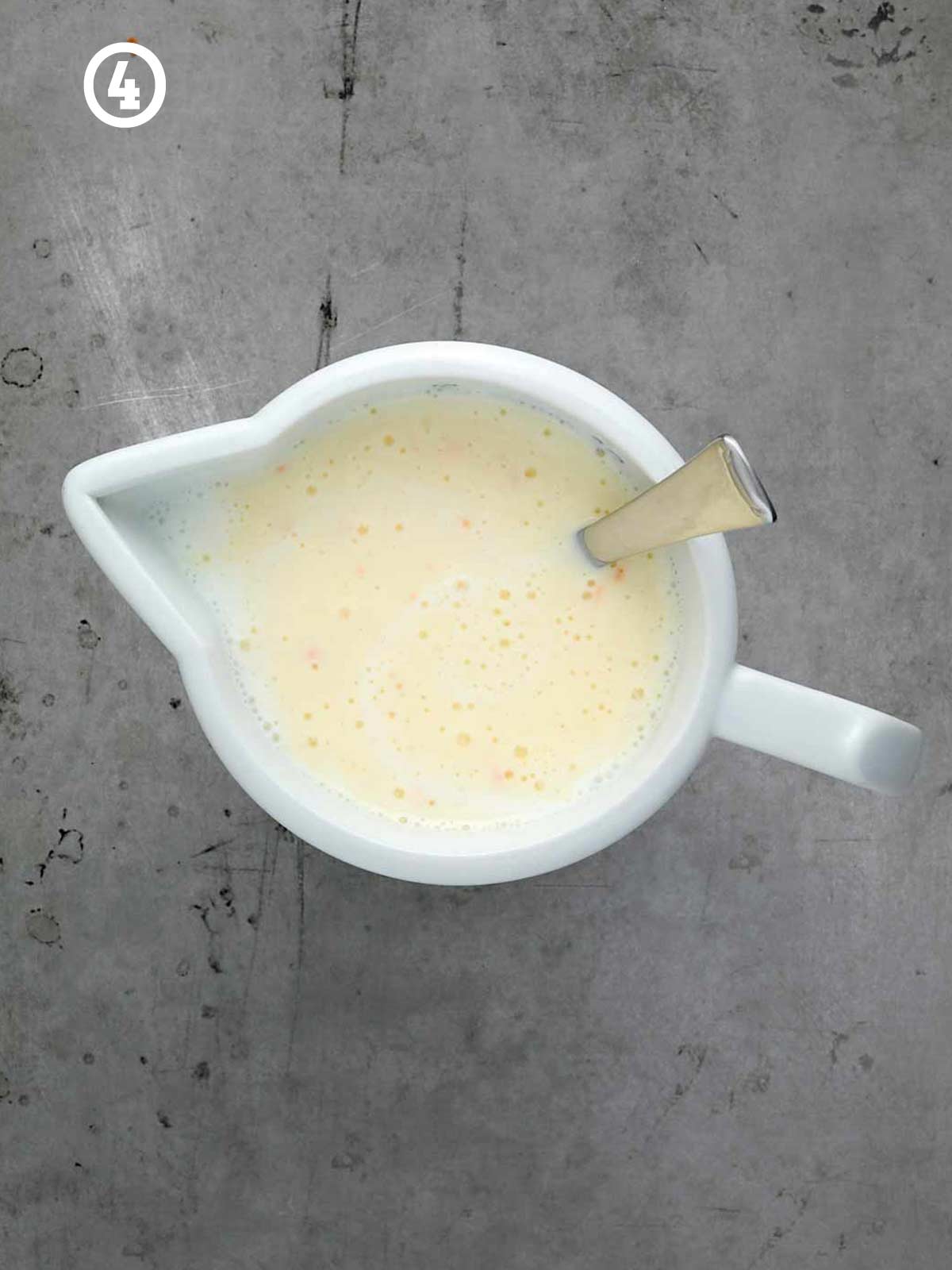 A white bowl with a spoon in it.
