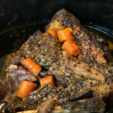 A crock pot full of meat and carrots.