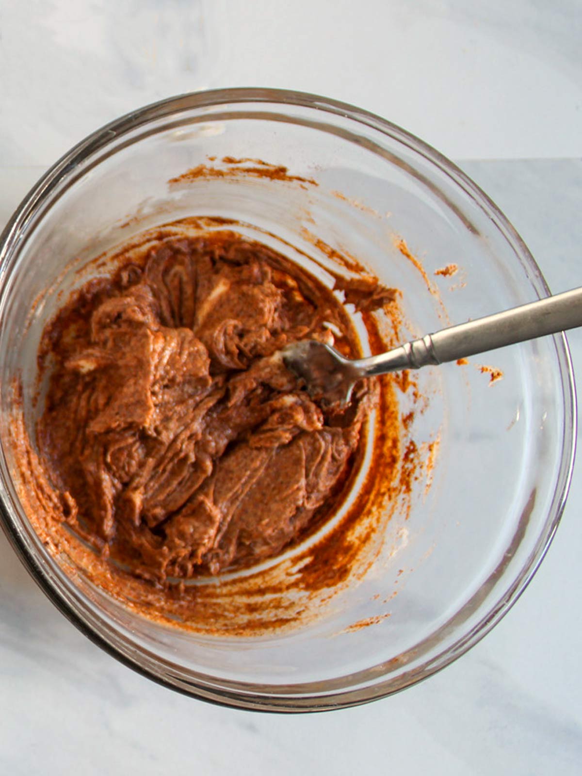 A bowl of chocolate batter with a spoon in it.