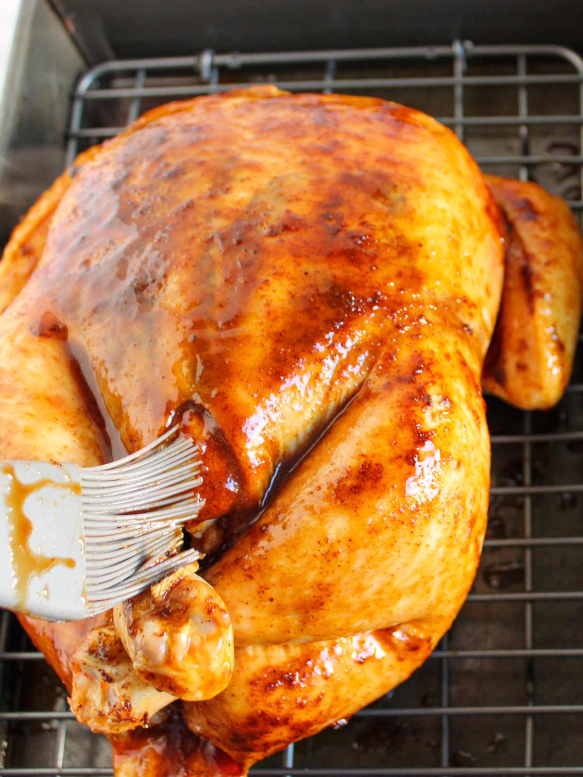 Chicken being basted with a mixture of butter and BBQ sauce.