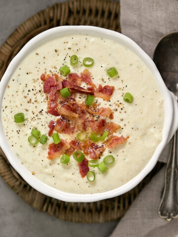 A bowl of soup with bacon and green onions.