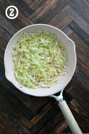A frying pan of shredded cabbage in butter and oil.