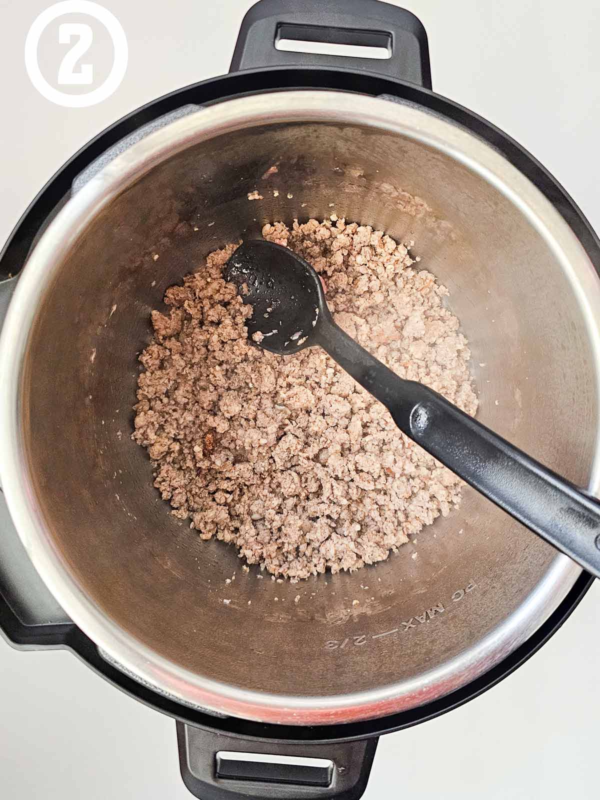 A pot of ground meat with a spoon.