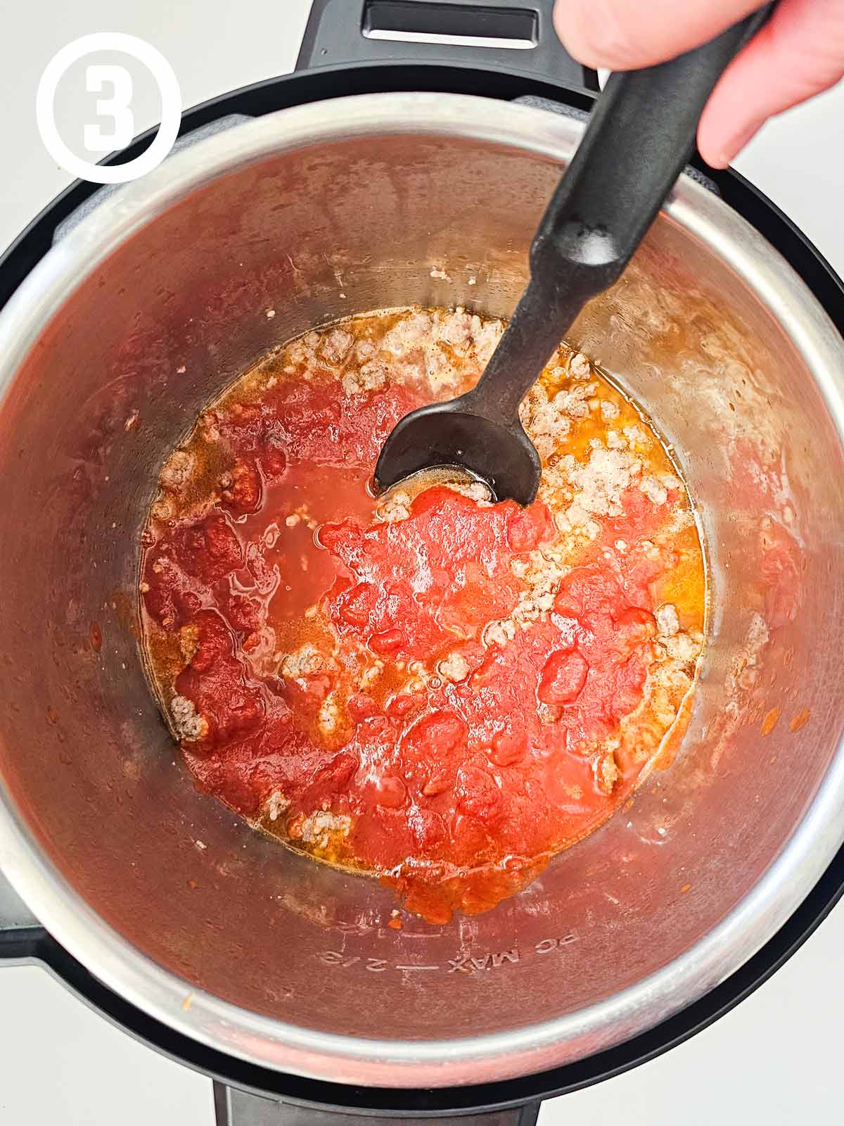 A person stirring a sauce in a pot.