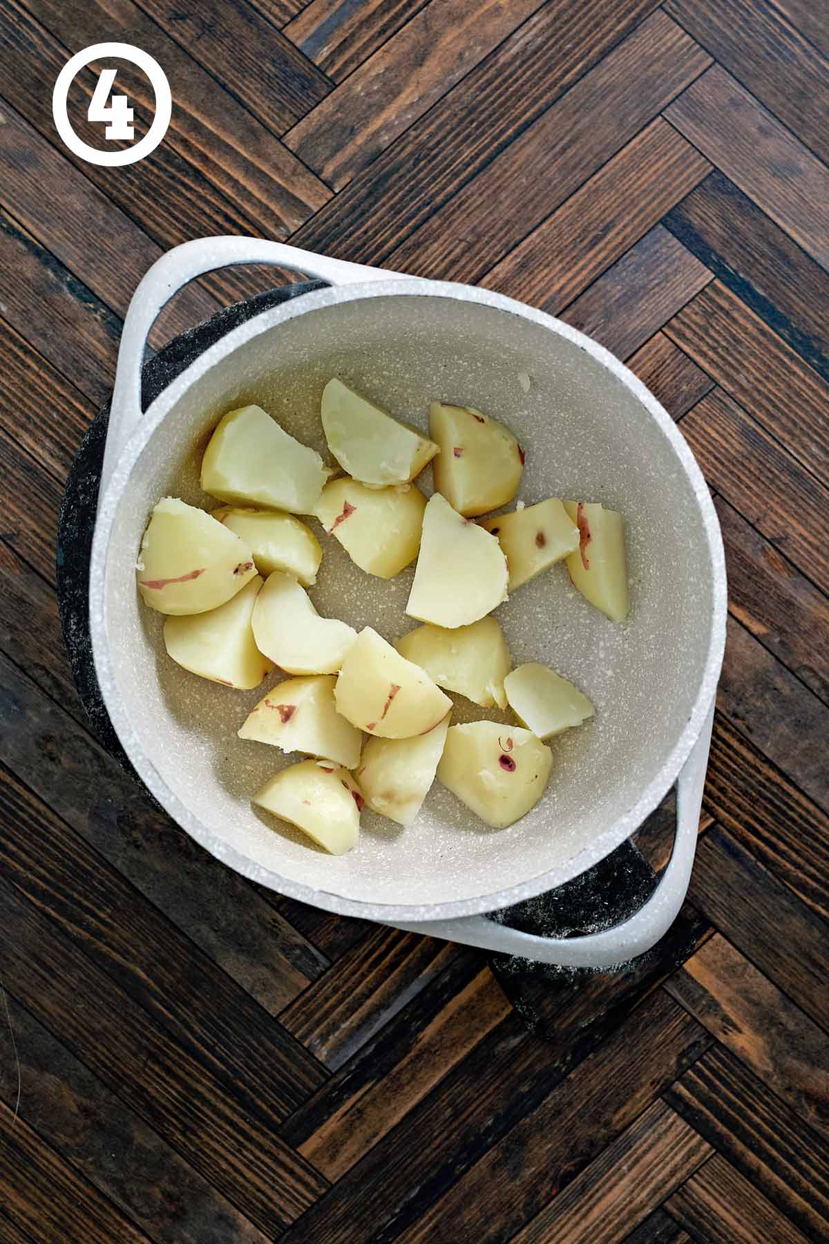 A pot with cooked and drained red potatoes.