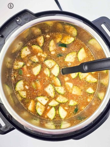 A pot of Mexican vegetable soup with zucchini in it.