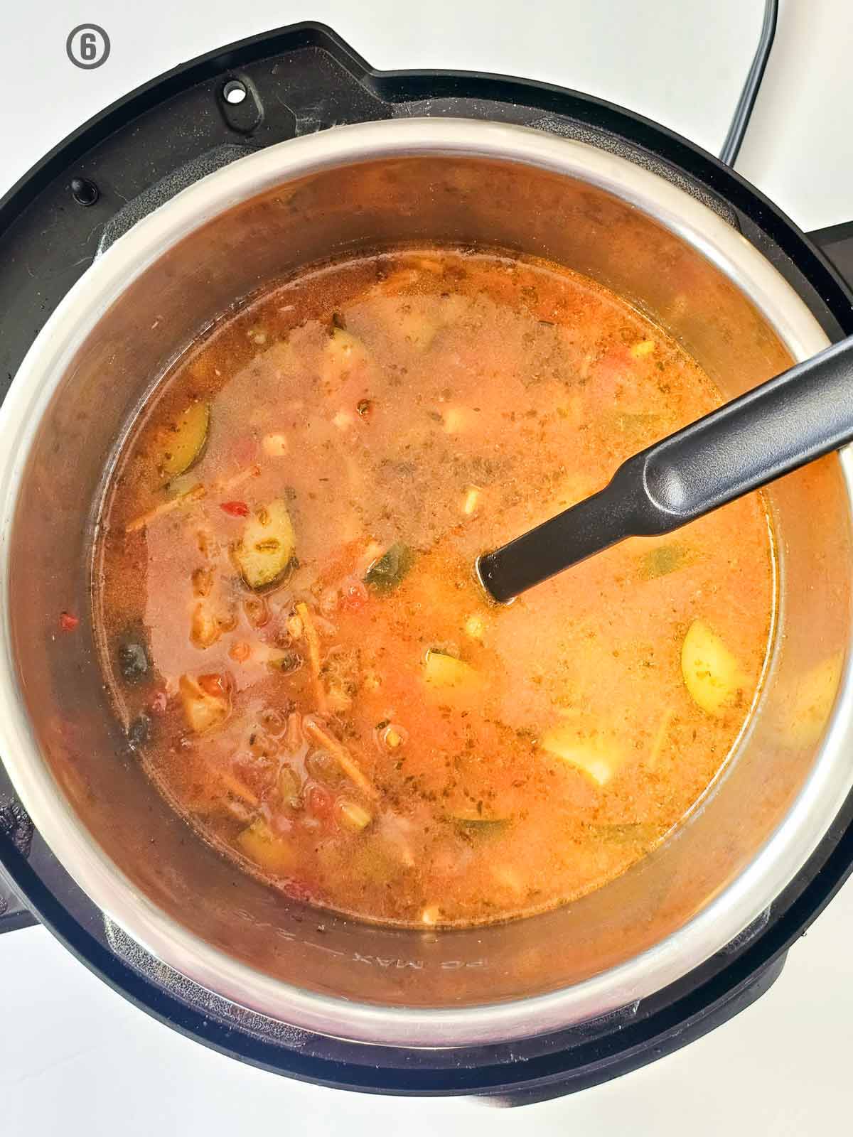A pot of Mexican vegetable soup with a spoon.