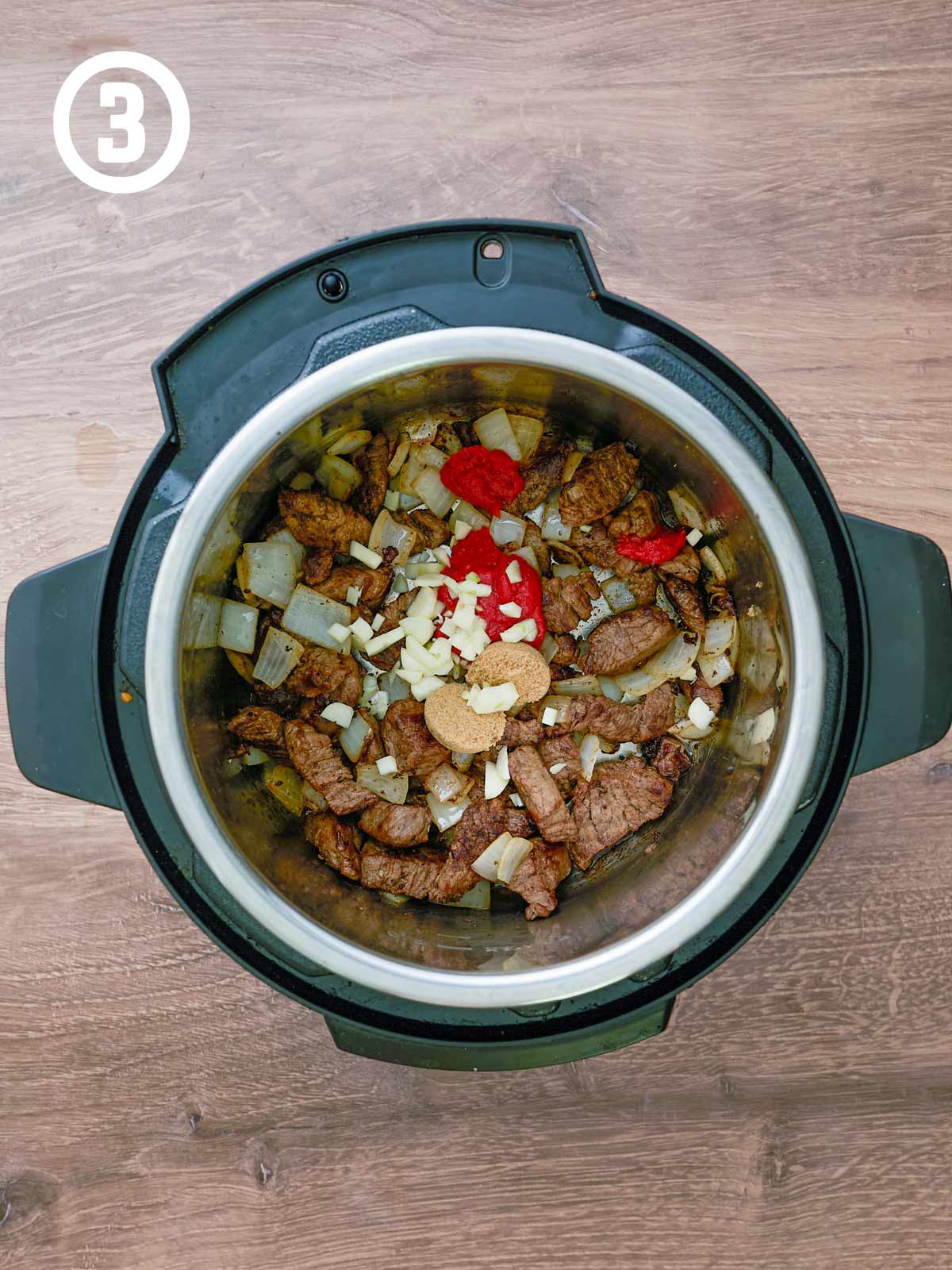 An instant pot filled with meat, garlic, brown sugar, and tomato paste.