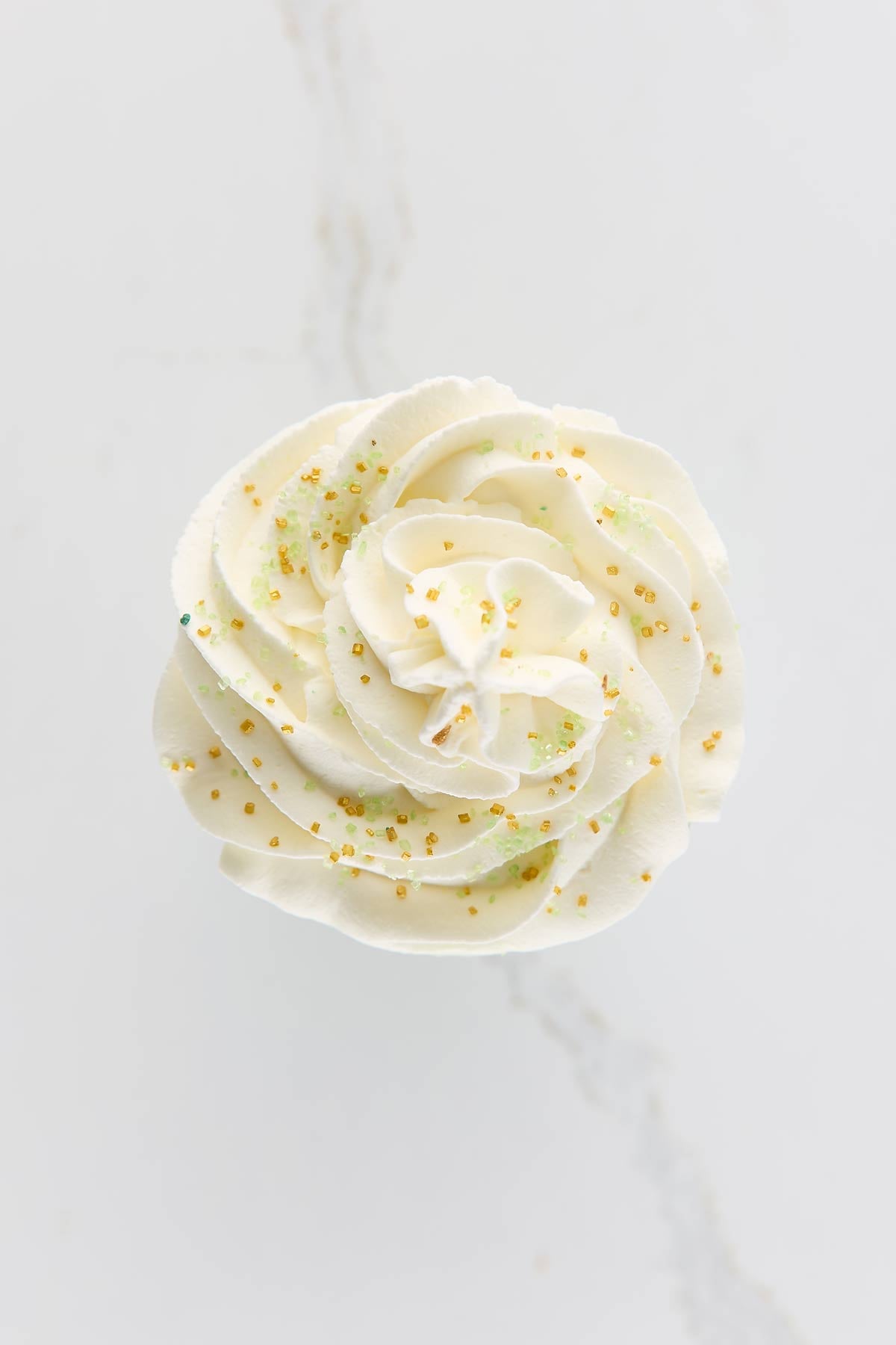 Whipped cream with small yellow and green sprinkles, viewed from above.