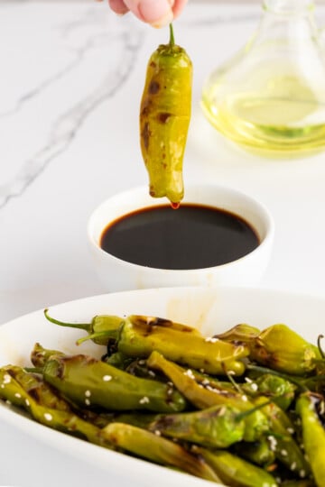 Dipping a blistered shishito pepper in ponzu sauce.