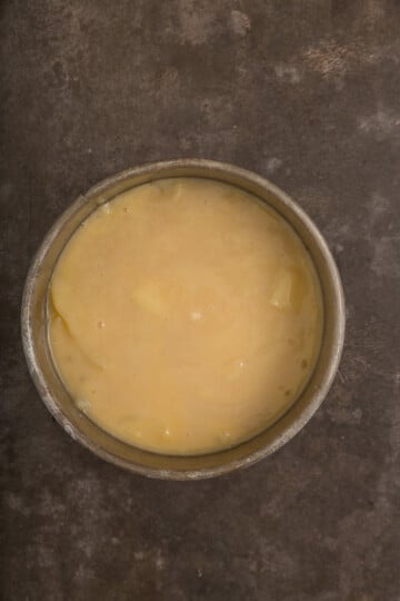 A bowl filled with creamy, light yellow custard placed on a dark, textured surface.