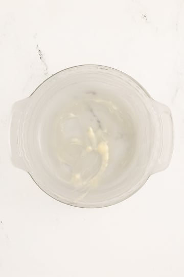 A glass mixing bowl with a small amount of white residue on the sides and bottom, placed on a light-colored surface.