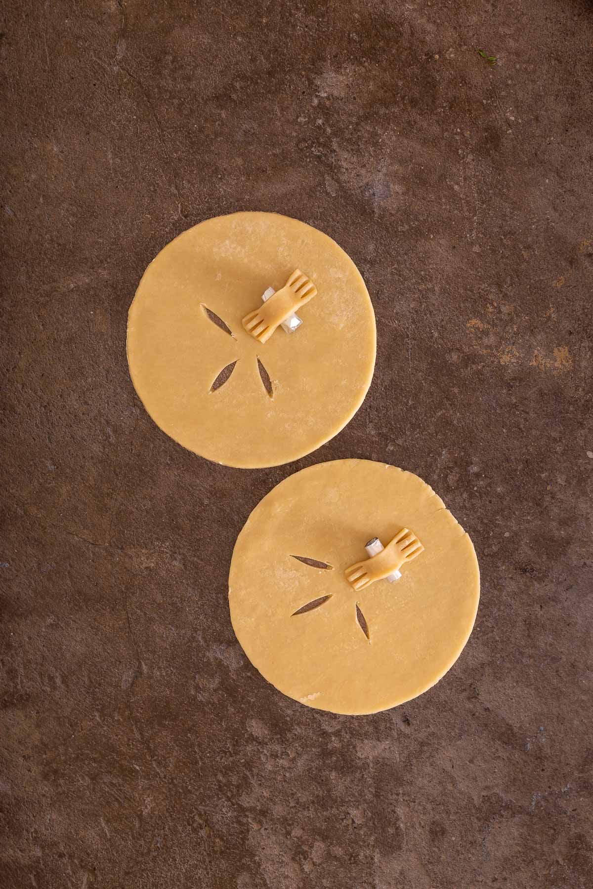 Two round pieces of dough with slits and small plastic sand dollar molds rest on a brown textured surface, ready to inspire your next sheet pan pancakes from mix.