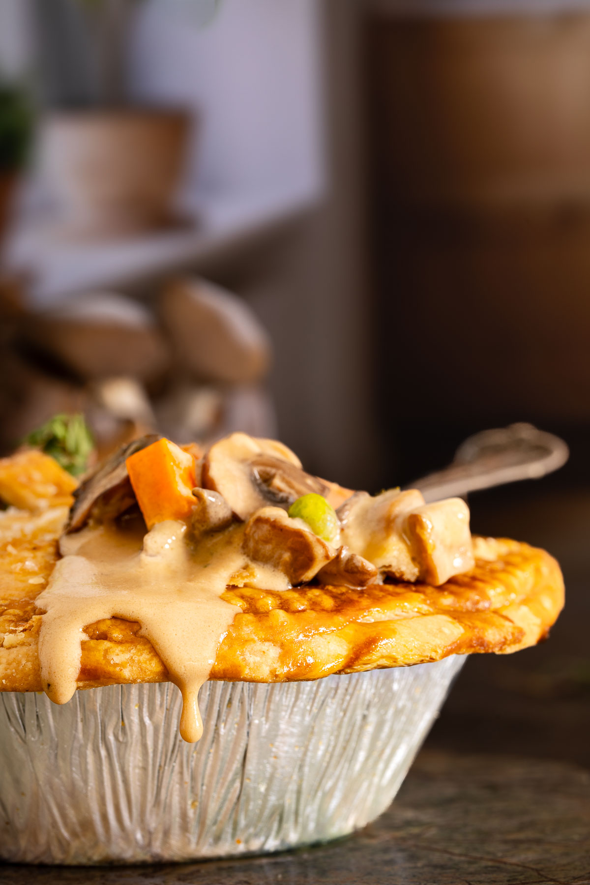 A close-up of a savory pie in a foil tin, topped with creamy sauce and chunks of vegetables and meat, with a fork resting on top—perfect comfort food, just like your favorite sheetpan pancake recipe.