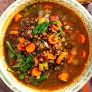 A bowl of carrot and lentil soup containing wild rice, celery, and spinach.