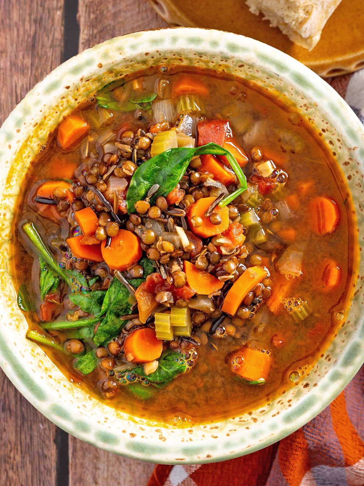 A bowl of carrot and red lentil soup with spinach, carrots, and wild rice.